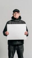 A mysterious old man in a black jacket holds a blank white sign photo