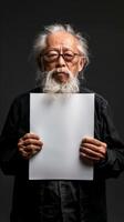 A Chinese old man stands solemnly, holding a white blank sheet of paper photo