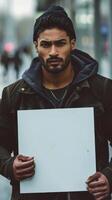 A man, sad expression, holds a blank sign in a street photo
