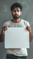 A man holds a white sign in front of his face photo