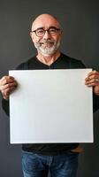 Mature man with a warm smile holding a blank white board photo