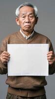 A wise Chinese elder holds a blank white board in his hands photo