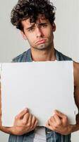 A melancholic man holding up a blank white board photo