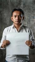 A contemplative man holds a blank white board in his hands photo