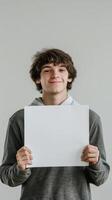 Smiling young man holds up a blank white board photo