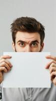 A man holds a blank white board in front of his face, hiding his emotions photo