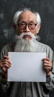 A wise old man with a flowing white beard holds a blank white sign photo