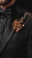 A man in a tuxedo proudly displaying a boutonniere on his lap photo
