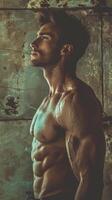 A shirtless man confidently stands in front of a textured wall photo
