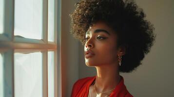 A black woman with an afro stares out a window photo