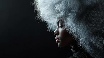 A woman with a large, silver afro, looking down in contemplation photo
