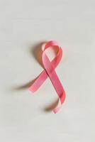 Minimalistic Pink Ribbon Symbolizing Cancer Awareness on White Background photo
