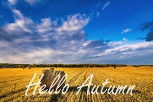 The words Hello Autumn on the background of field with golden haystacks. Greeting card. The concept of the beginning of autumn. photo