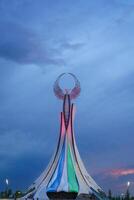 UZBEKISTAN, TASHKENT - AUGUST 15, 2023 Monument of Independence in the form of a stele with a Humo bird on a twilight in the New Uzbekistan park in summer. photo