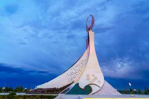 UZBEKISTAN, TASHKENT - AUGUST 15, 2023 Monument of Independence in the form of a stele with a Humo bird on a twilight in the New Uzbekistan park in summer. photo