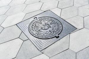 The cover of a sewer manhole on the pavement, with the inscription Zaryadye in Russian. photo