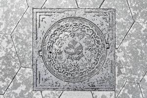 The cover of a sewer manhole on the pavement, with the inscription Zaryadye in Russian. photo