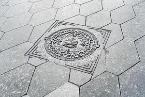 The cover of a sewer manhole on the pavement, with the inscription Zaryadye in Russian. photo