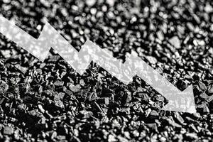 Arrow down on coal background. The concept of falling prices, mining, import, export, production or sales of coal. photo