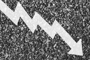 Arrow down on coal background. The concept of falling prices, mining, import, export, production or sales of coal. photo