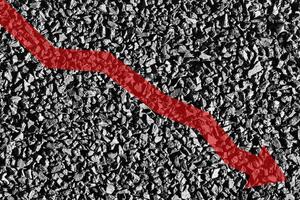 Arrow down on coal background. The concept of falling prices, mining, import, export, production or sales of coal. photo