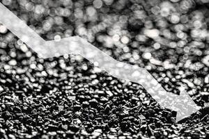 Arrow down on coal background. The concept of falling prices, mining, import, export, production or sales of coal. photo