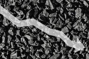 Arrow down on coal background. The concept of falling prices, mining, import, export, production or sales of coal. photo