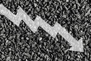 Arrow down on coal background. The concept of falling prices, mining, import, export, production or sales of coal. photo