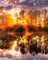 Sunrise on the pond in the autumn morning with birches and fog. photo
