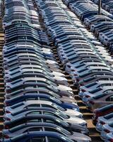 Rows of a new cars parked in a distribution center on a car factory on a sunny day. photo
