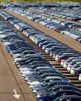 Rows of a new cars parked in a distribution center on a car factory on a sunny day. photo