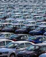 Rows of a new cars parked in a distribution center on a car factory on a sunny day. photo
