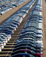 Rows of a new cars parked in a distribution center on a car factory on a sunny day. photo