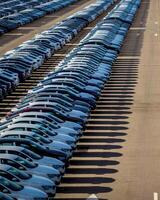 Rows of a new cars parked in a distribution center on a car factory on a sunny day. photo