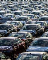 Rows of a new cars parked in a distribution center on a car factory on a sunny day. photo
