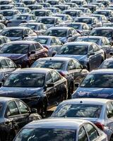 Rows of a new cars parked in a distribution center on a car factory on a sunny day. photo