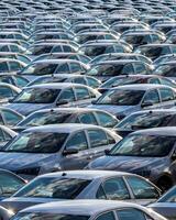 Rows of a new cars parked in a distribution center on a car factory on a sunny day. photo