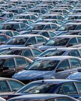Rows of a new cars parked in a distribution center on a car factory on a sunny day. photo