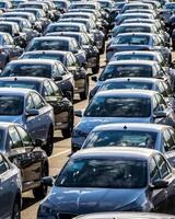 Rows of a new cars parked in a distribution center on a car factory on a sunny day. photo