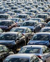 Rows of a new cars parked in a distribution center on a car factory on a sunny day. photo