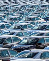 Rows of a new cars parked in a distribution center on a car factory on a sunny day. photo