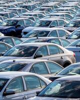 Rows of a new cars parked in a distribution center on a car factory on a sunny day. photo