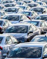 Rows of a new cars parked in a distribution center on a car factory on a sunny day. photo