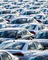 Rows of a new cars parked in a distribution center on a car factory on a sunny day. photo
