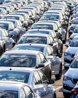 Rows of a new cars parked in a distribution center on a car factory on a sunny day. photo