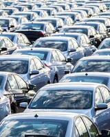 Rows of a new cars parked in a distribution center on a car factory on a sunny day. photo