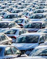 Rows of a new cars parked in a distribution center on a car factory on a sunny day. photo