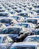 Rows of a new cars parked in a distribution center on a car factory on a sunny day. photo