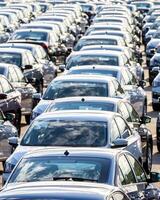 Rows of a new cars parked in a distribution center on a car factory on a sunny day. photo