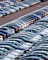 Rows of a new cars parked in a distribution center on a car factory on a sunny day. photo